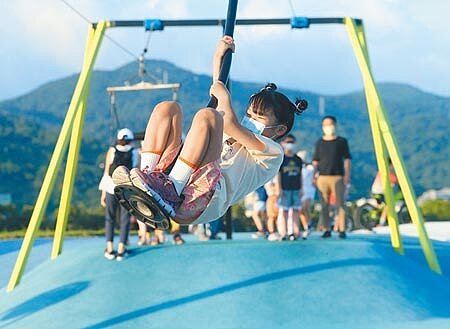 18日是微解封的首次假日,傍晚時分,小朋友開心玩著大佳河濱運動公園遊憩設施,享受久違戶外玩耍的樂趣。(陳怡誠攝)