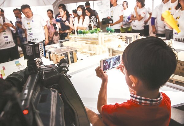 市長柯文哲昨參觀「2015台北設計城市展」，大批媒體包圍訪問柯文哲，卻有一個小小粉絲搶到最前面，用手機一直錄著柯文哲的一舉一動。 記者楊萬雲／攝影