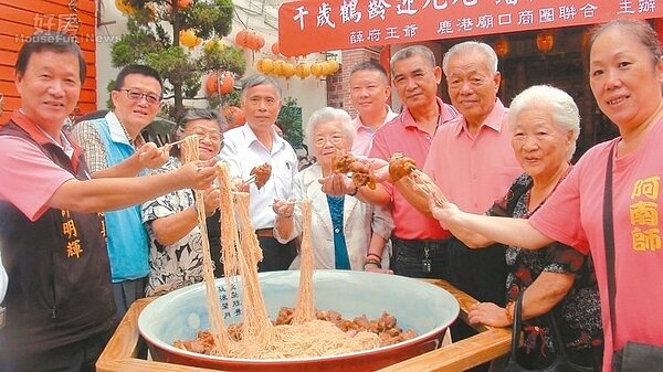 鹿港阿公阿嬤從大碗公內拉起長長麵線，象徵延年益壽、長命百歲。 記者郭宣彣／攝影