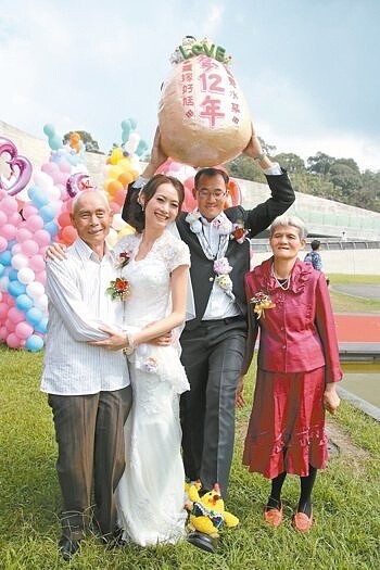 日月潭舉辦集團結婚,愛情長跑12年的賴怡妏(左二)與楊冠英(右二)帶著大蛋,象徵等12年「等」到了水某與好尪。 記者黃宏璣/攝影