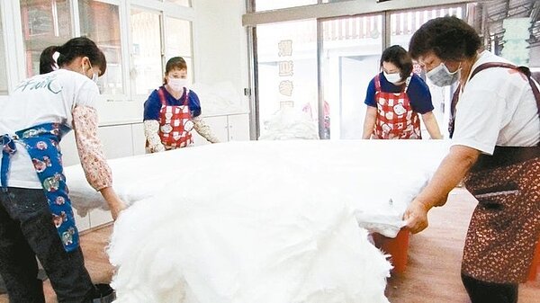 氣溫驟降,台南市下營農會蠶絲被熱銷,工人忙碌其中。( 記者謝進盛/攝影)