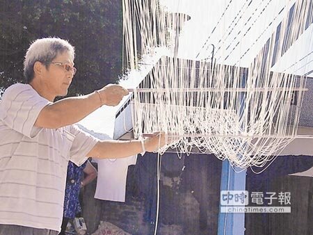 曾連興用竹竿把糾結的細麵撥開,烈日當頭眼睛睜不開,需靠墨鏡防紫外線傷害。(王文吉攝)