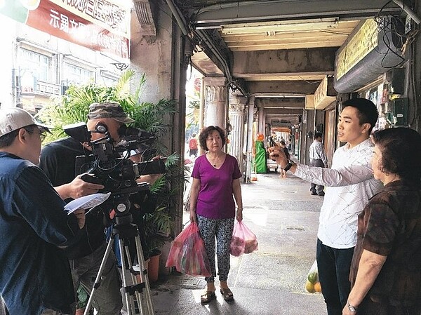 市府研考會昨天在新化老街,為「OPEN 1999」手機App拍攝宣導片,同時宣導「騎樓暢通」,由當地素人阿嬤當演員,過程輕鬆有趣。研考會主委趙卿惠表示,未來市民看到騎樓違規占用等,透過App就可上傳照片檢舉。 (圖/吳淑玲攝)