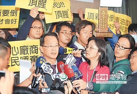 
彰化地方法院審理頂新飼料油案27日一審宣判，被告魏應充等6人全判無罪；魏應充委任律師羅豐胤（前排左）庭外受訪時抗議人士在身後高舉標語，甚至秀出「食安靈位」表達不滿。（范揚光攝）
 