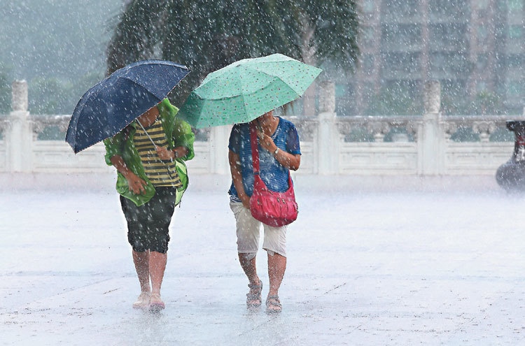 受到颱風外圍環流影響，台北市間歇下起大雨，二名到故宮的遊客雖撐傘拉著褲腳，仍淋成落湯雞。  記者邱德祥／攝影