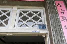大門屋簷上還可以看到早期用的門牌號碼以及水、電申請核准之後釘上去的銘牌，這些在現在生活中幾乎已經絕跡。
大門上的窗框為白色格菱紋排列，並且使用玻璃，左右窗框中間與下方處都有藝術雕刻，顯示當年屋主的身價不凡。