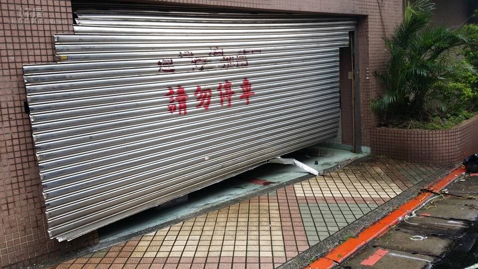 車庫鐵捲門抵擋不住狂風暴雨的摧殘，幾乎快要掀起來了。（網友提供）