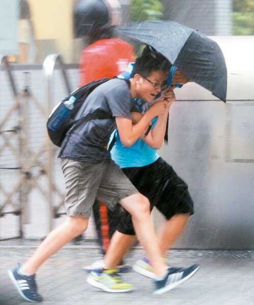 台北市昨天午後下起傾盆大雨，二名學生共撐一把傘拔足狂奔。 記者蘇健忠／攝影