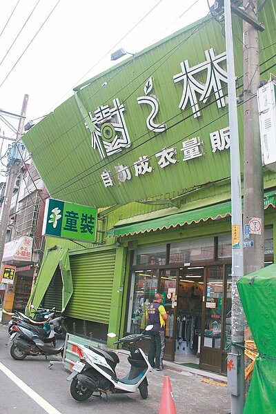 平鎮區樹之林店面的招牌,因為蘇迪勒颱風,上半部被吹倒,搖搖欲墜的鐵皮壓在前方高壓電線上,很危險。 記者葉臻/攝影