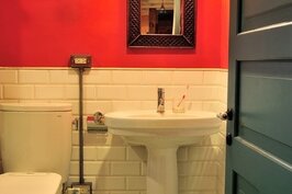 客廳旁的洗手間以綠白相間的磁磚，搭配大紅色牆面，用色強烈大膽，卻不突兀，常常讓造訪客人留下驚喜。