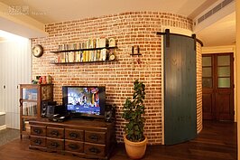 主臥床鋪前方的紅磚牆轉角處砌成圓弧形，門後是更衣室，不僅極具特色，成為家裡一大亮點，同時也拓寬走道的寬度。