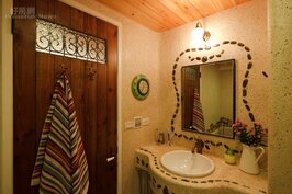 主臥浴室的洗手台鋪上抿石子，鵝卵石則沿著鏡面及檯面繞行，透露著不規則的隨興。