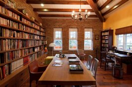 閣樓工作室採光良好，紅磚堆砌而成的主牆面，搭配開放式木頭書櫃與木頭長桌，同樣洋溢舒服的鄉村風情。