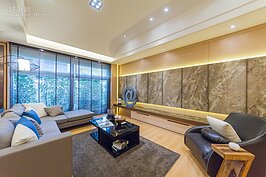 客廳全貌。電視牆部分貼上美麗花紋的深色薄石板，可增加視覺的穩定性。其中石板上的花紋又與木紋類似，可呼應室內空間的古典設計主軸。不過石材貼面雖然可營造質感，在部分時候卻會顯得較為冷冽，想要使用石材面作為裝飾時要多注意。