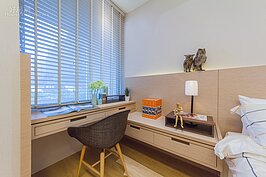 對窗的化妝台平時可作為書桌使用。值得注意的地方就是化妝台與床頭邊桌並非同一高度，而是使用有高低落差的設計，這樣可增加室內的空間變化，並營造出立體感。