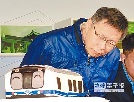 台北市市長柯文哲出席北捷通車20周年慶生會時，仔細端詳捷運造型的蛋糕。（顏謙隆攝） 