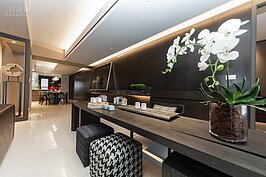 在客廳沙發後方黑色木質壁面共有三間房間。三間房同在一邊是現代已經少見的格局設計。不過在此，這樣的排列方式可保證每間房間都擁有可導入光線的對外窗。
在客廳與房間之間的長廊區域，除了皮質沙發營造質感外，深色的木紋桌與馬賽克布質座椅，搭配著泡茶組，營造出一股濃濃的中國風。