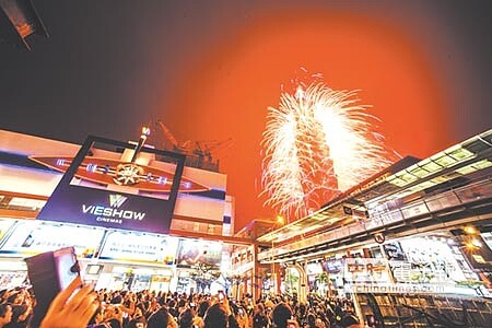 民眾拿起手機錄下今年台北101煙火畫面。圖/郭吉銓