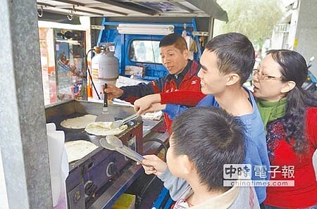 
退伍士官長鍾旭輝（後排左一）開著蔥抓餅餐車造訪育幼院、社福單位，免費煎餅請弱勢孩童吃。（郭韋綺攝）
 