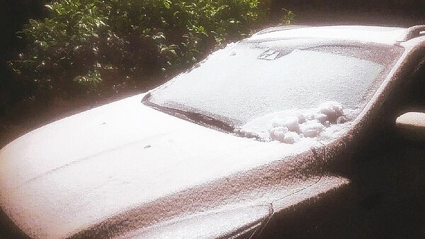 海拔九六七公尺的新北市烏來信賢里山區,路旁汽車昨晚一身雪白,疑似下雪,但氣象局推測可能是冰霰。 記者王長鼎/翻攝