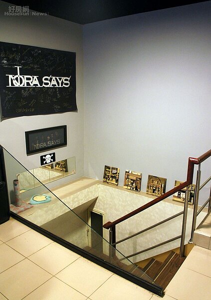 5.通往地下室的牆面上,掛著一張斗大的Nora Says團名掛布以及全體團員肖像表框畫。