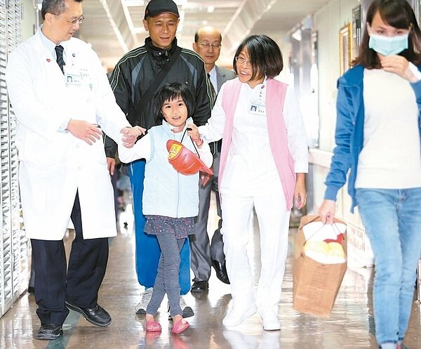 震災中受困六十一小時獲救的八歲小妹妹林素琴,在奇美醫院治療恢復狀況良好,醫院昨下午三點五十七分讓她出院。她帶著救難人員送的簽名工程帽走出病房,露出靦腆笑容向照顧她的醫護人員致謝,媽媽(右一)與爸爸(左二)在旁跟隨。 記者劉學聖/攝影