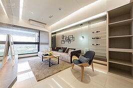 客廳部，沙發上方為主要支撐涼，為了不讓坐在這裡的人感受到壓迫感，使用間接照明為修飾手段。地磚部分採用60x60耐磨石英磚，搭配柔和的燈光，讓生活主要區域的客廳更顯得柔和。