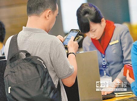 包括台灣在內多國的航空公司,在美聯邦航空總署強烈建議下,三星Note 7機上全程禁用。圖為旅客在華航報到櫃台前使用手機。(范揚光攝)
