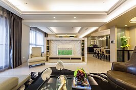 客廳是居住者生活起居的中心，因此質感與傢俱搭配就十分的重要。設計師在客廳部分採雙色的概念進行設計，天花板與電視牆為白色色系，但是沙發與沙發卓則是採深色系統，看似衝突卻又十分的調和。