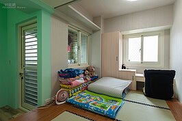 兒童房採傳統日式臥房的樣子。靠近對外曬衣場的牆面漆成綠色，房間內還有手作的榻榻米鋪陳在上，靠窗處則是做了固定式書桌與小衣櫥，足夠這個年紀的小朋友收納與念書使用。