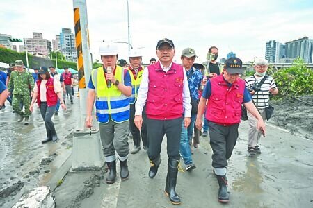 
新北市長侯友宜（前排中）12日上午新莊區利濟橫移門旁的重新堤外道，視察積土清理情形。（吳嘉億攝）
