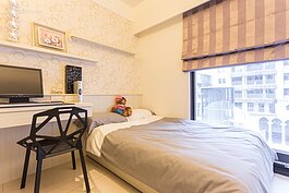 另外一間房間一看就知道是小孩房，床頭壁面除了貼活潑圖案的壁紙外，也做了了組簡單陳列板，不論是模型或者是卡通公仔都可展示。大片的落地窗雖然能引入明亮的戶外光線，但不能開啟則是較為不便的地方。