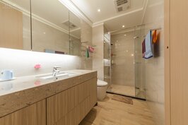 共用浴室在檯面採用莊重又不失活潑的石材，為了讓整體空間感加大，櫥櫃部分採用全鏡面的款式。但是需注意的是隨著時間以及使用浴室盥洗的次數增加，鏡面部分須更花心思照顧。