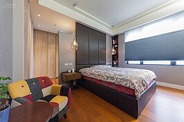 屋主兒子睡的次主臥也是有大片面外的窗戶，整個裝潢設計上簡單俐落，沒有多餘華而不實的設計。左下角多色拼布的單人沙發讓整體空間顯得十分活潑。