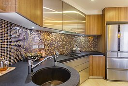 傳統塑料流理台用久了難免會產生深色又難以清理的刮痕，而且也不適合在上面放加熱後的鍋具，因此在流理臺特別選用深色日本人造石檯面，牆面角度重新塑造略成為U字形，讓女主人在此烹調更為順手。