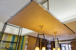 為了讓燈具不會因為包梁所造成的高低差長度所有不同，因此在餐桌上方設計師利用不鏽鋼架與人造皮做出承板，營造出視線統一高度的感覺。