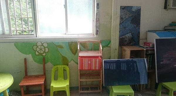 6.	學童的小椅子和並置的畫作，是真切的生活風景。
