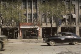 1957年中山北路三段21號的樣子。畫面左邊模糊的車影是軍方的大卡車，右邊黑色的黑頭車想必裡面的乘客不是高官就是有錢人。較為特別的是21號原址是一間酒吧。