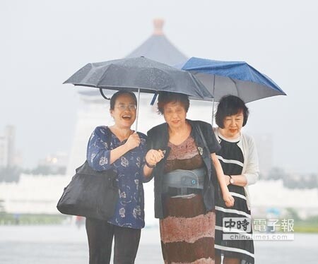 對流雲系發展旺盛，北部地區下午突然降下雷陣雨，在中正紀念堂參觀的三位民眾共持兩把傘避雨。未來一周，民眾出門，最好隨身攜帶雨具。（圖文：陳怡誠）