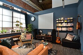 投影機與老式音響的搭配，加上大量CD與吉他，佈置讓客廳彷彿小型電影院。