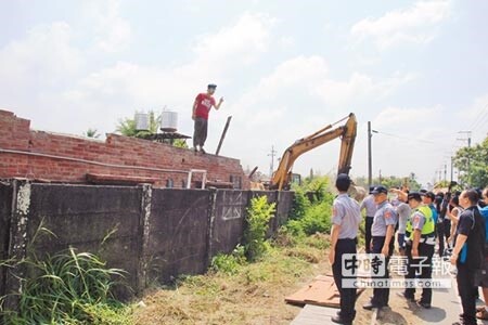 西港外環道開闢工程，工務局在15日進行地上物拆除，擔憂西港糖鐵軌道遭破壞，以反西港外環道不當開闢自救會為首的團體，出面抗爭，並爬上建築物試圖阻擋工程進行。（莊曜聰攝）