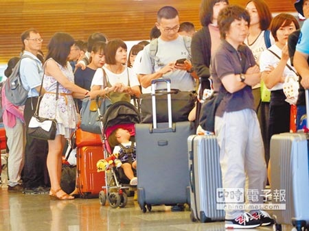 受尼莎颱風影響，桃園機場許多航班延誤或取消，一群旅客正在排隊準備報到登機。（范揚光攝）