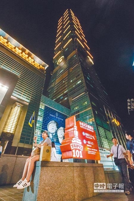 101前廣場一名陸客團導遊正等待團員。(中時)