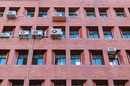 一台台冷氣高掛在紅色二丁掛磁磚上，形成一個特別又彷彿來到香港小區生活中的相同氛圍。