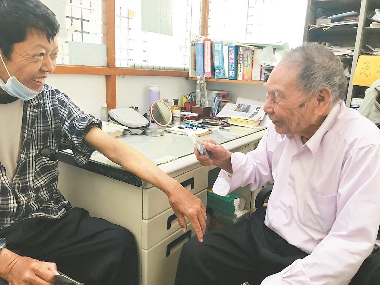 九十九歲張始鵬醫師（右），每天仍坐鎮診所，與患者大多有數十年老交情，看診之餘也會話家常。 記者王慧瑛／攝影