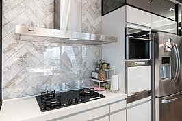 廚房最惱人的莫過於煎煮炒炸所產生的油煙會附著在牆面上。為了方便清理，設計師將磁磚面再覆蓋上一層透明壓克力板，這樣的做法既可顯示牆面美麗的磁磚圖案，又能簡單清理油煙。