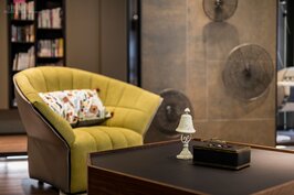 客廳中多角度的木質茶几，棕色的溫潤色彩與個人沙發躺椅以及牆面相呼應，呈現強烈居家風格。