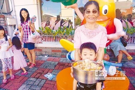 不少民眾帶鍋碗瓢盆來裝,一位阿嬤和孫子裝滿剉冰,幸福全寫在臉上。(李其樺攝)