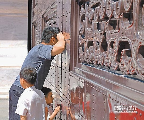 想看銅像撲空的民眾不甘心,嘗試透過門縫一窺究竟。(實習記者宋以安攝)