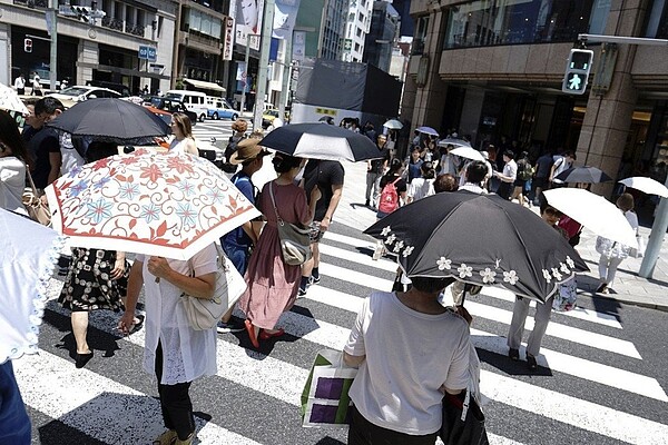 日本連日酷暑,東京許多行人廿日撐傘抵擋熱浪。 (美聯社)